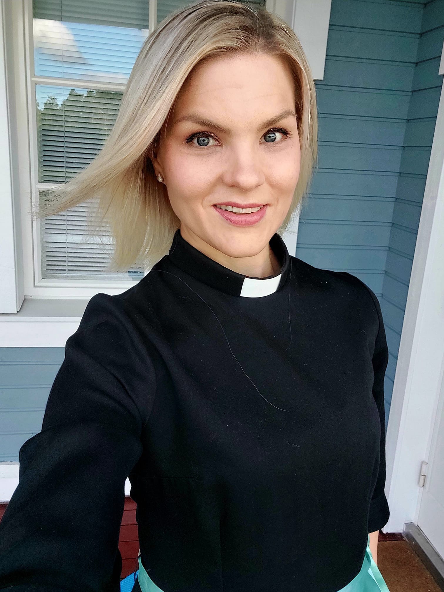 Hymyilevä henkilö papin asuun pukeutuneena.